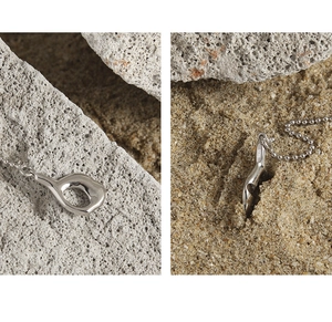 Detail of S925 sterling silver organic pendant on a beaded chain over natural stone