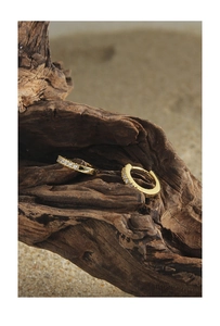 Detail shot of gold huggie earrings with cubic zirconia pavé on a rustic wood background