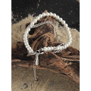 Elegant multi-layer pearl necklace with silver water drop pendant on natural wood base
