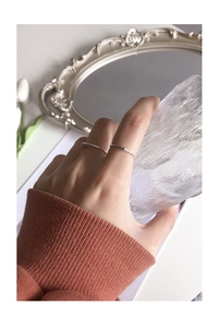 Dettaglio di anelli minimalisti in argento sterling S925 con trama di metallo liquido sulla mano