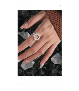 Makro-Detail eines unregelmäßig texturierten S925 Silberrings an der Hand vor Kristallen
