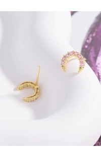 Macro view of gold crescent earrings with pink zircons on a white artistic base