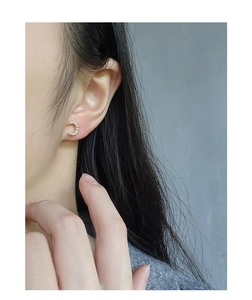 Detail of a crescent moon earring in gold finish with white pavé crystals on a model