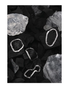 Detailed view of silver rings set with sparkling textures on charcoal and white stones