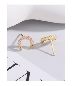 Macro shot of crescent-shaped gold stud earrings with pink zirconia stones and fine bead detail
