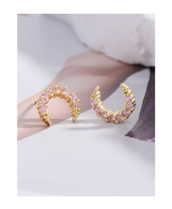 Macro detail of gold-plated crescent earrings featuring pink round-cut cubic zirconia