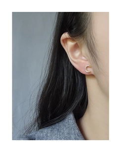 Detailed close-up of a gold crescent moon stud earring with sparkling zircon on a model