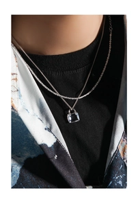 Detail of layered S925 silver necklace featuring a square crystal lock pendant on model