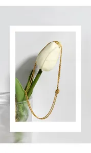 Collier en argent S925 plaqué or avec détail nœud posé sur une tulipe blanche