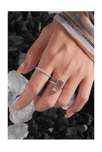 Detail of S925 silver ring set with rectangle zircon on hand with mineral background