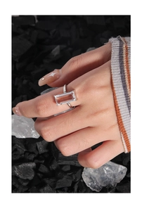 Detail shot of rectangular pink gemstone ring with silver band on model hand