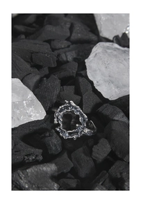 Makroaufnahme von S925 Sterlingsilber Ring mit Lavatextur auf dunkler Holzkohle im Detail
