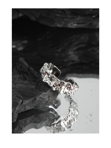 Macro detail of silver S925 ring with irregular lava texture and red zircon stones
