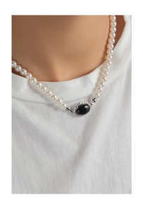 Detailed view of elegant pearl necklace featuring a central oval black agate pendant