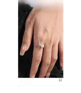 Detailaufnahme eines Silberrings mit unregelmäßiger Textur und weißer Perle am Finger