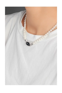 Close-up of pearl necklace with oval black agate pendant and crystal halo on collarbone