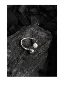 Makroaufnahme S925 Silberring mit Perle und Totenkopf auf Holzkohle Hintergrund
