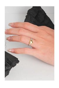 Detail of twisted silver band ring with golden heart worn on finger over dark coal