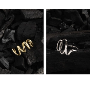 Close-up of S925 sterling silver wavy rings showing detail of the hallmark on charcoal