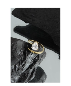 Macro detail of a golden pear-cut zircon ring on charcoal reflecting minimalist luxury