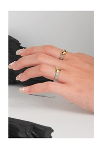 Detail of twisted silver band and golden heart ring on hand with minimalist styling