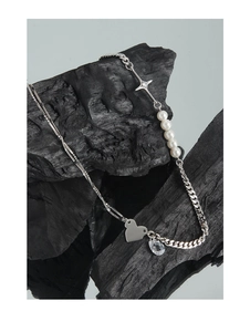 Detail of S925 silver necklace with pearls, heart charm and star pendant on dark stone