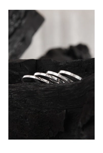 Detailed view of silver textured rings with vertical stripes on dark charcoal background