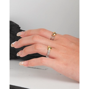 Minimalist S925 sterling silver twist rings with gold heart accent on female hand