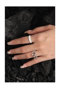 Detailed view of silver twist wavy ring and textured wide band on charcoal background