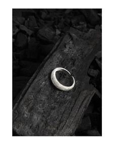 Macro detail of S925 sterling silver ring with frosted sand texture on black charcoal