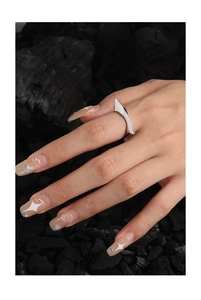 Detailed view of silver geometric ring on finger with charcoal stone background