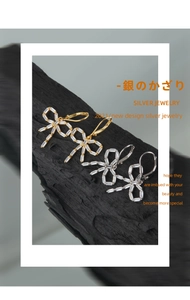 Macro detail of S925 silver bow earrings with rectangular zircon on black charcoal