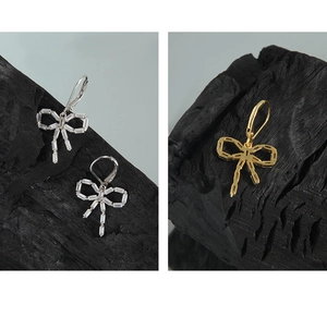 Macro shot of S925 silver bow earrings with rectangular zircon stones on dark wood