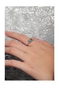 Detailansicht eines unregelmäßigen Silberrings mit blauem rechteckigem Zirkonia am Finger