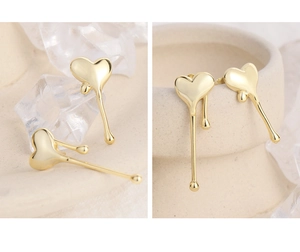 Macro shot of liquid metal heart earrings in gold finish with modern artistic design