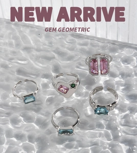 Macro detail of S925 sterling silver heart and geometric gemstone rings on water glass