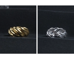 Detail of gold and silver croissant rings featuring textured twist design on dark surfaces