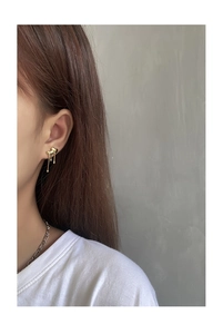 Close-up of golden liquid heart tassel earrings worn by a model in a modern style