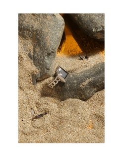 Detail view of silver chain texture ring with black rectangular inlay on volcanic rock