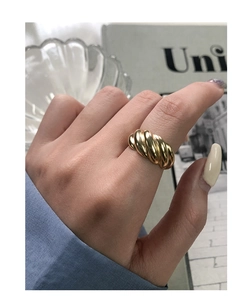 Close-up of a gold-plated croissant twisted ring worn on finger with elegant styling