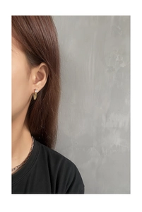 Detail of gold tassel earrings with square zircon on model with minimal grey background