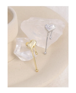 Macro shot of liquid metal heart earrings in gold and silver finish on a mineral stone