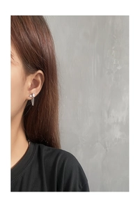 Detail of S925 sterling silver chain earrings with geometric cubic zirconia studs on ear