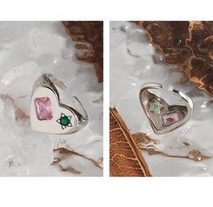 Detail of silver heart ring with pink rectangular zircon and green star-set gemstone