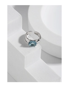 Macro detail of an oval blue zircon ring with a S925 silver band on minimalist props