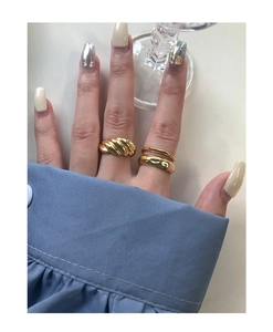Detail of croissant dome ring and double layer irregular gold ring worn with blue shirt
