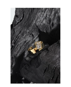 Dettaglio macro di un ampio anello d'oro con zircone rettangolare su carbone nero
