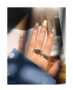Detailed view of silver rings featuring oval blue zircon on light blue shirt fabric background