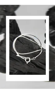 Close-up of a double-layered S925 sterling silver snake chain bracelet on a black charcoal base
