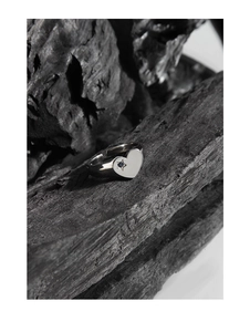 Detail of silver heart signet ring featuring a small blue star-shaped zircon inlay